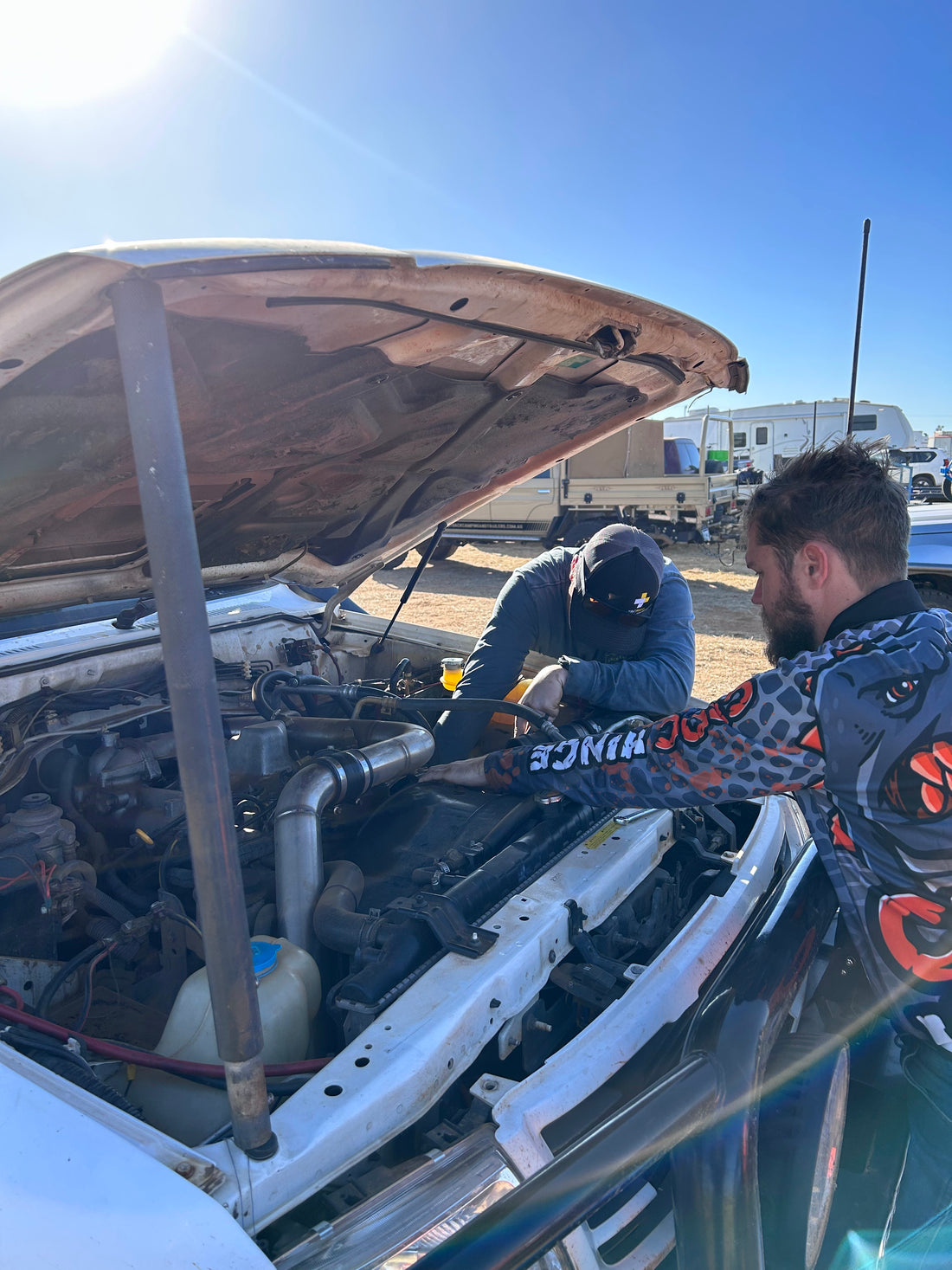 Two people working in an engine bay, man closest is wearing a Croc Hinge long sleeve sun smart shirt